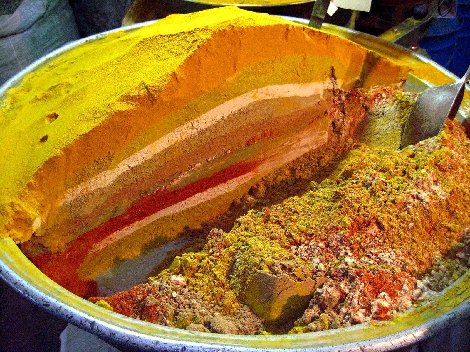 Mounded piles of colorful ground spices at a spice stall in Isfahan's Grand Bazaar