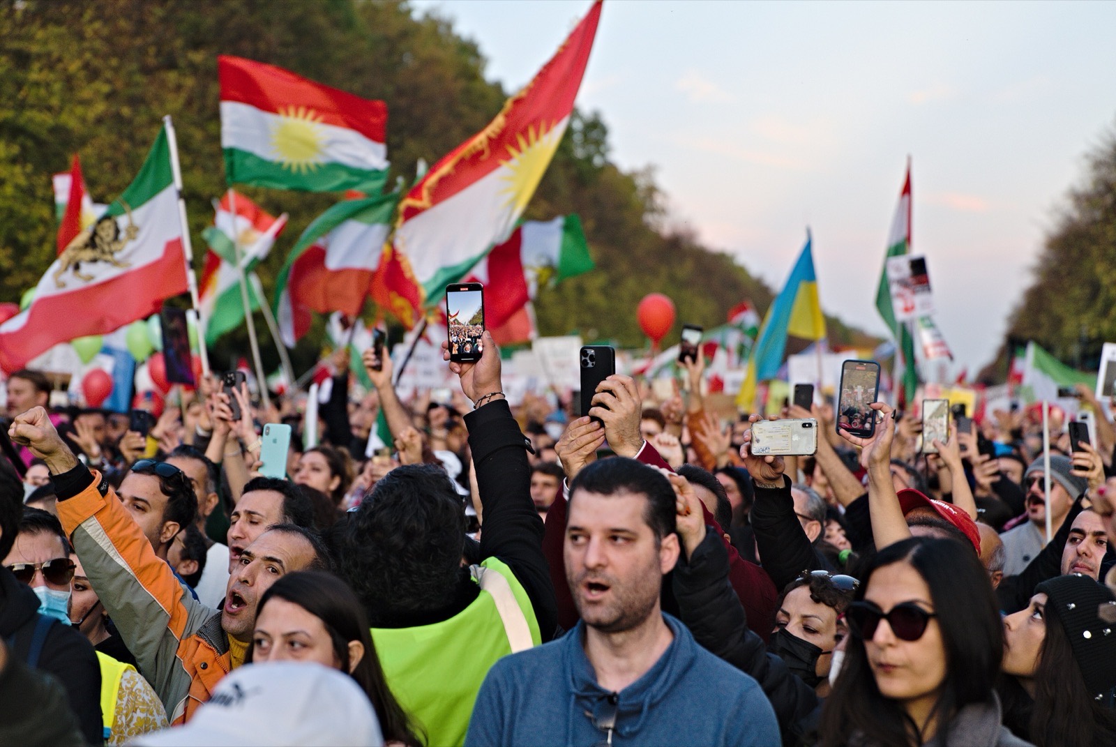 ایرانیان در میانِ پرچمهای شیر و خورشید مشتهای خود را بالا بردهاند، در گردهماییِ «زن، زندگی، آزادی»، برلین، ۲۰۲۲